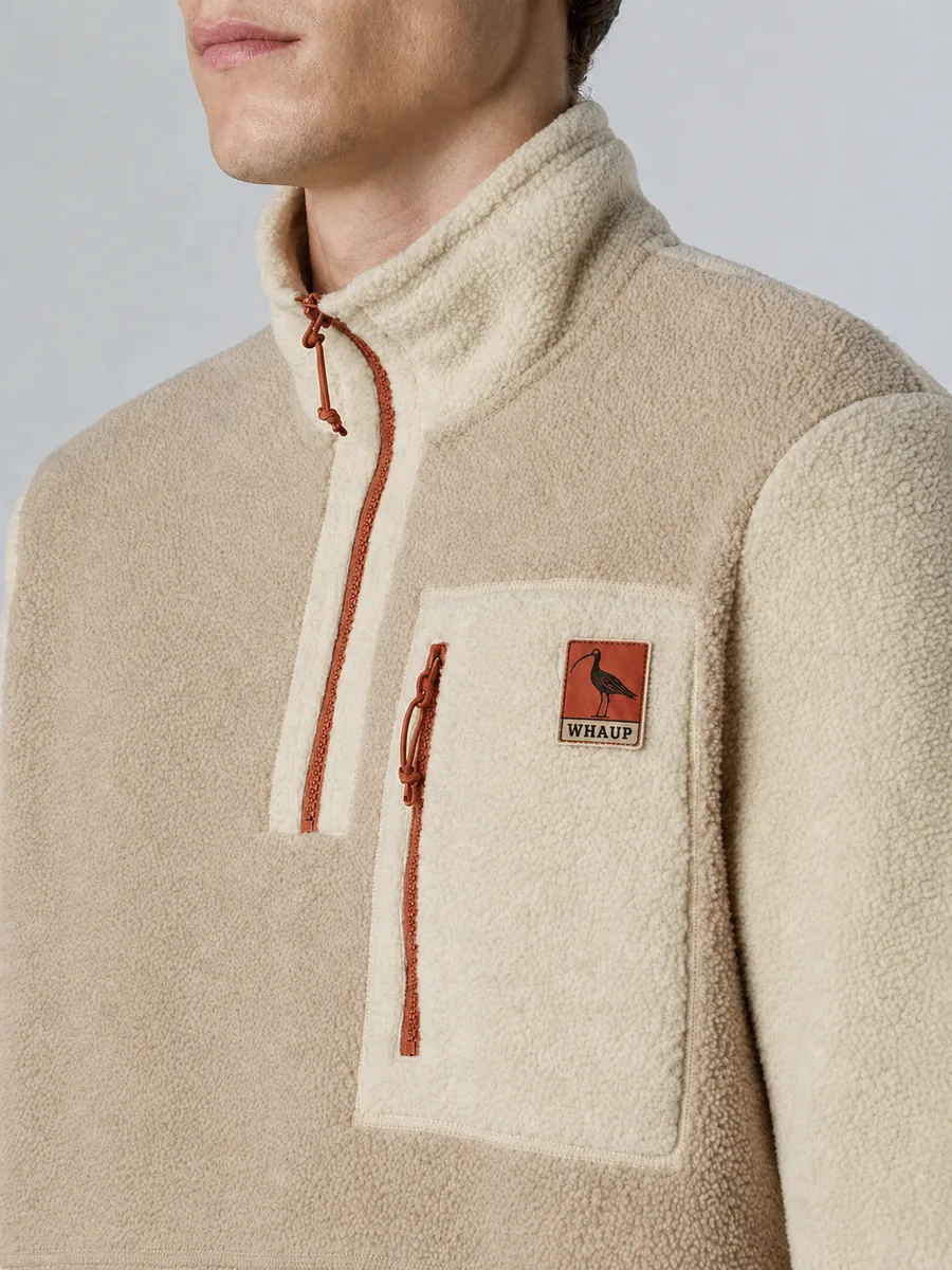 A cream fleece half-zip with terracotta zips and a woven Whaup Press patch on the chest pocket.